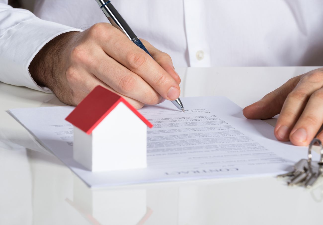 Ein Richterhammer und ein Miniaturhaus auf einem Schreibtisch